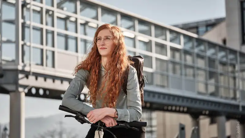 Eine nachdenkliche Frau mit roten Haaren auf ihrem Fahrrad
