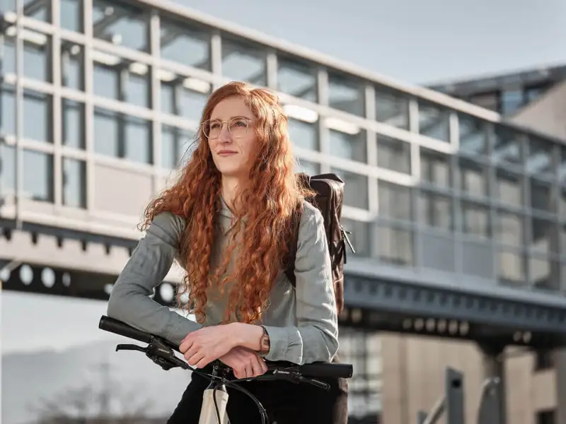 Eine nachdenkliche Frau mit roten Haaren auf ihrem Fahrrad